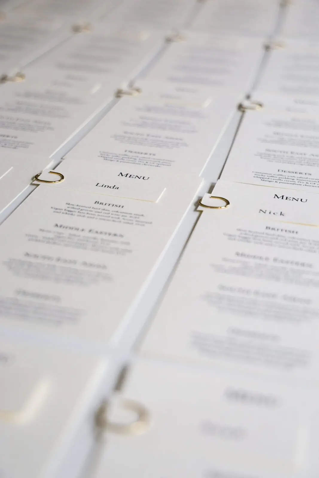 White and gold wedding menus with gold wedding ring details ready to display.