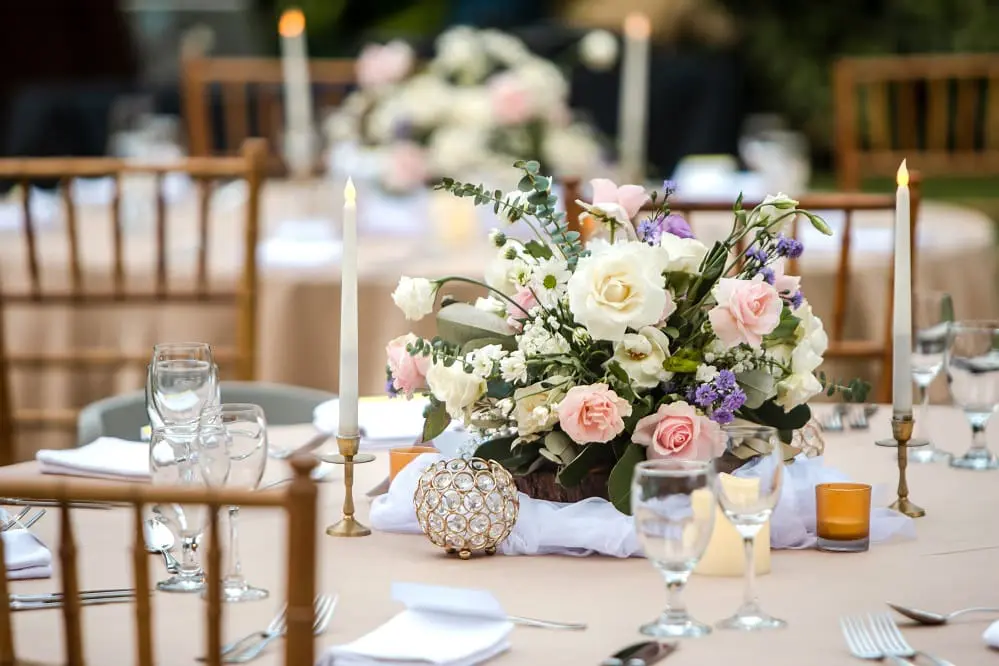 Beautiful table setting with tableware, candles, flowers, accessories and rose centerpiece for a party, wedding reception, gala banquet or other holiday event.