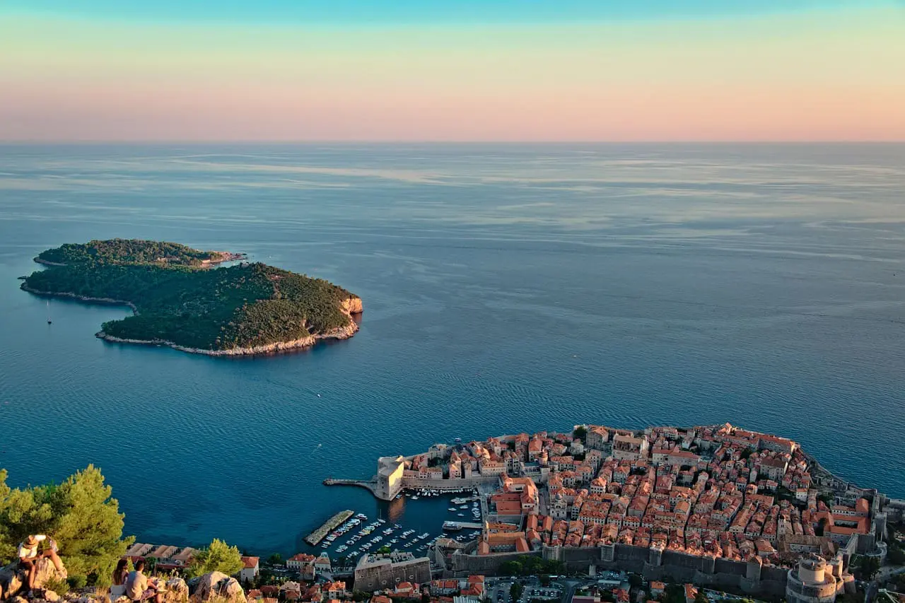 An image of Dubrovnik at sunrise with the glistening sea and houses by the coast.