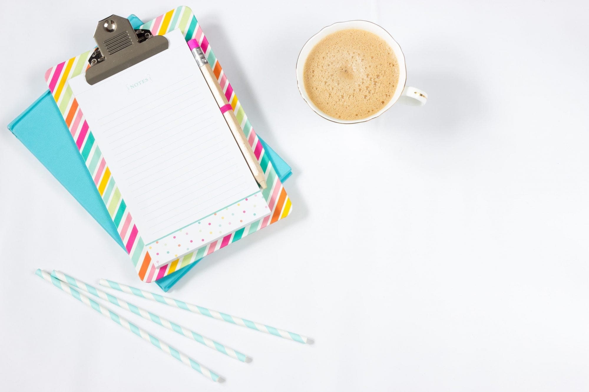 A clipboard with a cup of coffee and a notebook next to it, perfect for wedding planning or wedding services professionals.