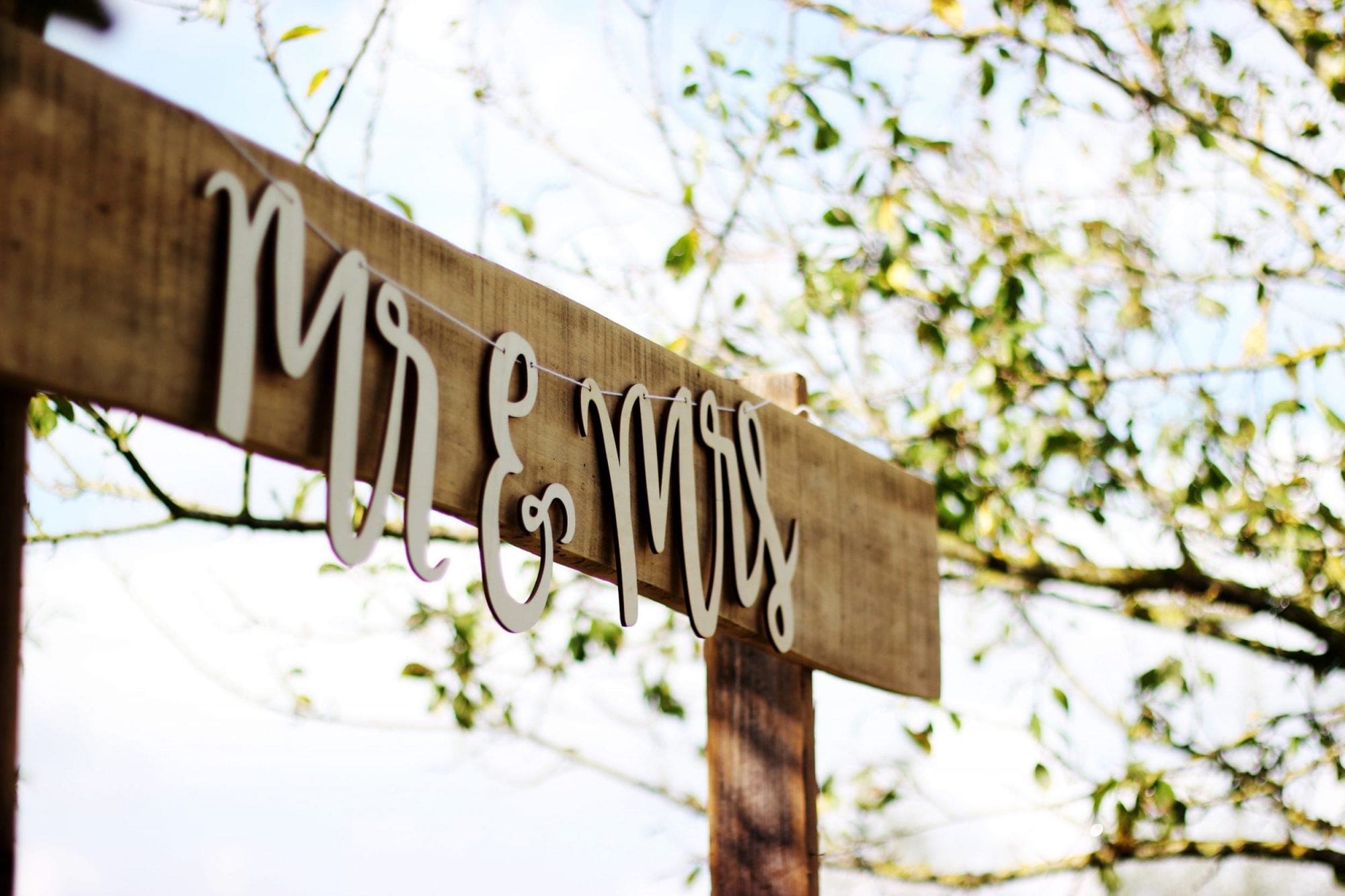 A wooden sign for wedding services, with mr and mrs written on it.